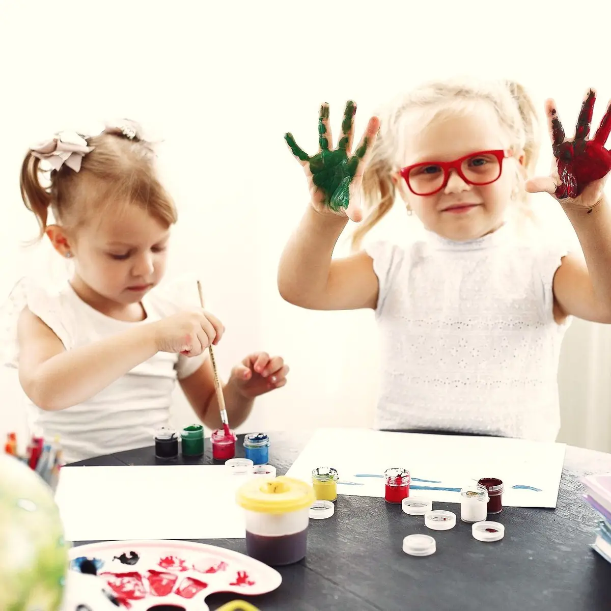 Two students showing off paint covered hands
